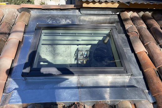 Fenêtre de toit avec abergement en zinc sur une toiture en tuiles