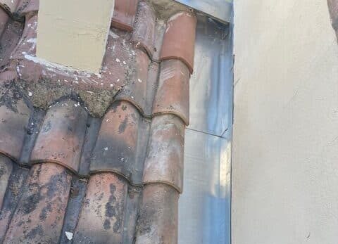 Bande de solin en zinc le long d'un mur, toiture en tuiles