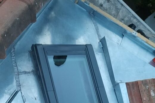 Fenêtre de toit avec son abergement en zinc sur une toiture en tuiles